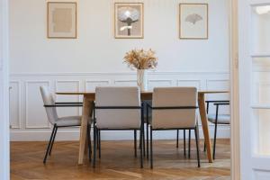 einen Esstisch mit Stühlen und eine Vase aus Blumen in der Unterkunft Luxury typical Parisian apartment in Saint-Ouen
