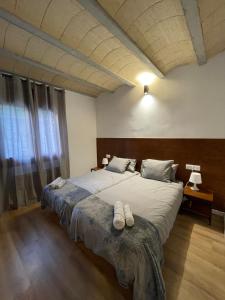 1 dormitorio con 1 cama grande y 2 zapatillas en Casa de la Mestra, Espinalbet - ALBERGA, en Castellar del Riu