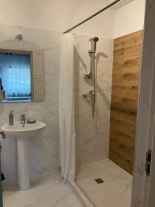 a white bathroom with a sink and a shower at Casa BABI in Căciulata