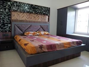 Schlafzimmer mit einem großen Bett mit einem Kopfteil aus Holz in der Unterkunft Vaidhya homes in Deoghar