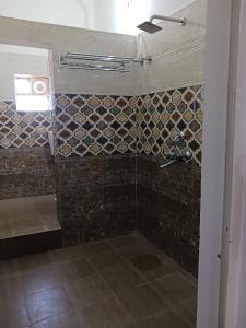 y baño con ducha y pared de piedra. en Vaidhya homes, en Deoghar