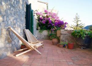 una silla de madera en un patio con flores en Cal Cisteller Argelaguer, en Argelaguer