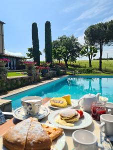 uma mesa com pratos de comida ao lado de uma piscina em Villa Arzilla Antica Residenza di campagna em Vitorchiano
