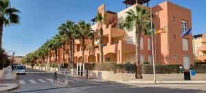 a building with palm trees in front of a street at Homes of Spain, Apartamentos Paraiso Vera Playa, Ed Tahiti, Atico B de 2 dormitorios con piscina privada en solárium y barbacoa, pie de playa in Playas de Vera