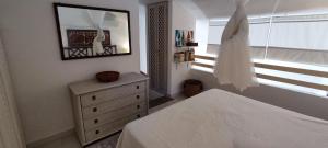 a bedroom with a bed and a dresser and a mirror at Villetta con giardino immersa nel verde a 150mt dal mare in Pula