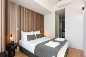 a bedroom with a large bed with white sheets and green pillows at ORM Batalha Apartments in Porto