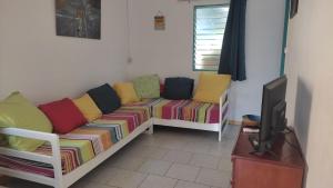 ein Wohnzimmer mit einem Sofa und einem TV in der Unterkunft Noukatchimbe Bungalow avec piscine partagée pour 2 à 4 personnes in Le Marin