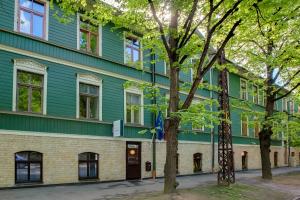 un edificio verde con alberi di fronte di Janne Hotel a Riga