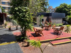 a group of wooden tables and chairs on a red rug at HOTEL BL in Puerto Iguazú