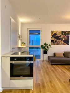 a kitchen with a stove and a living room at Modern Studio Gardenia_Gartenwohnung Alte Donau in Vienna