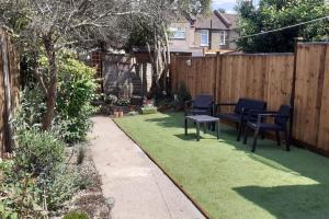 a backyard with chairs and a table and grass at 2BR Edwardian House in Greenwich in Abbey Wood