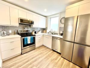 una cocina con armarios blancos y electrodomésticos de acero inoxidable en "Hike" at Hills Meaford, Pet Friendly, 2BD Suite en Meaford