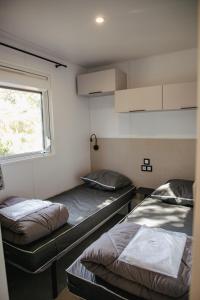 two beds in a room with a window at Camping Site de Gorge Vent in Fréjus