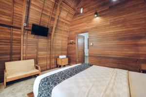 Schlafzimmer mit Holzwänden, einem Bett und einem Stuhl in der Unterkunft Tunjung Sari Villa Bedugul in Bedugul