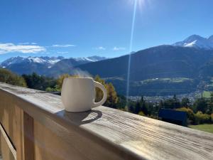 a coffee cup sitting on a wooden railing with a view at Meilerhof in Reith bei Seefeld