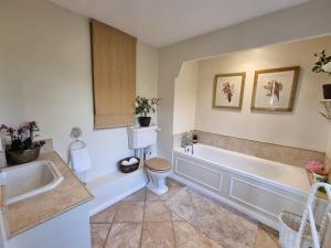 La salle de bains est pourvue d'une baignoire, de toilettes et d'un lavabo. dans l'établissement Gorgeous Country Cottage overlooking Windsor Castle, à Old Windsor