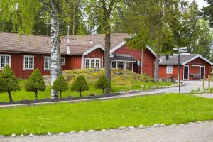 a red house with a grass yard in front of it at Odalgården Hotell, Kurs & Konferens in Marielund