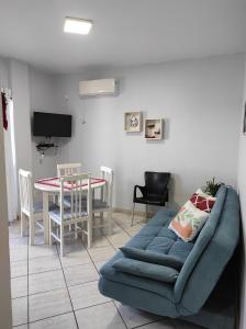 ein Wohnzimmer mit einem blauen Sofa und einem Tisch in der Unterkunft APTO 50M PRAIA- 4 PESSOAS, WIFI, SACADA, CHURRASQUEIRA, GARAGEM PARA VEICULOS PEQUENOS - Residencial Roveda in Bombinhas