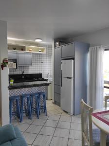 cocina con taburetes azules y nevera blanca en APTO 50M PRAIA- 4 PESSOAS, WIFI, SACADA, CHURRASQUEIRA, GARAGEM PARA VEICULOS PEQUENOS - Residencial Roveda, en Bombinhas