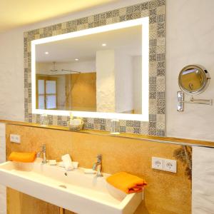 ein Badezimmer mit einem Waschbecken und einem großen Spiegel in der Unterkunft Hotel Maier zum Kirschner in Rottach-Egern
