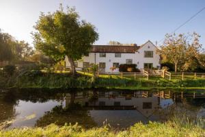 a house with a pond in front of it at Peaceful Riverside Five Bed Cottage in Somerset in Langport