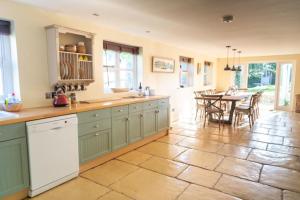 a kitchen with green cabinets and a dining room with a table at Peaceful Riverside Five Bed Cottage in Somerset in Langport