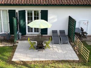 un patio con mesa, sillas y sombrilla en résidence KERLOREA studio 6, en Itxassou