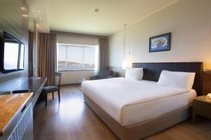una camera d'albergo con un grande letto e una TV di Kolin Hotel Spa & Convention Center a Çanakkale