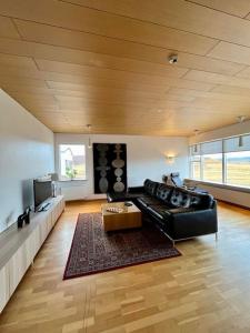 a living room with a black leather couch and a table at Fell cottage in Reykholt