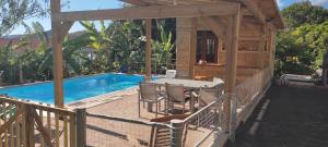 um deque com uma mesa e cadeiras ao lado de uma piscina em Noukatchimbe Bungalow avec piscine partagée pour 2 à 4 personnes em Le Marin