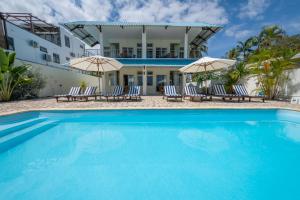a pool in front of a house with chairs and umbrellas at Beachfront Apartment - View to Die For in Triolet