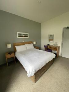 sypialnia z dużym łóżkiem i dwoma stołami w obiekcie The Caledonian Claymore Hotel w mieście Arrochar