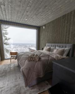 a bedroom with a large bed with a large window at Panorama Landscape Hotel in Nilsiä