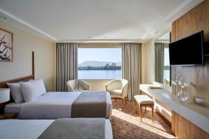 a hotel room with a bed and a desk and a window at Mövenpick Royal Lotus Monday Four Nights Luxor Friday Three nights Aswan in Luxor