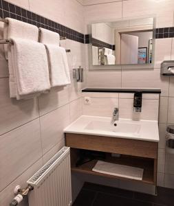La salle de bains est pourvue d'un lavabo, d'un miroir et de serviettes. dans l'établissement Hotel Altes Badehaus, à Bad Dürrenberg
