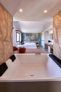 una grande vasca da bagno bianca in una camera con un letto di Nuovi Poderi Rooms a Senorbì