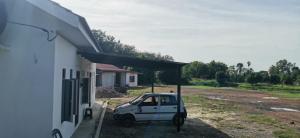 a small white car parked next to a building at Homestay D'kolam in Pendang