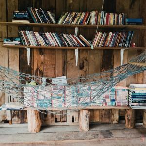 a hammock in front of a shelf of books at บ้านสวัสดีดอยเต่า 