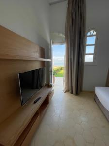 a bedroom with a tv and a bed and a window at Villa La Falaise in Oualidia