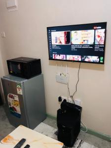 Elle comprend une télévision à écran plat suspendue sur un mur au-dessus d'un réfrigérateur. dans l'établissement Urban Escape, à Nairobi