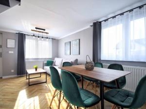 a living room with a table and green chairs at Top Alex domki Międzyzdroje in Międzyzdroje