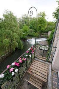a bench with flowers on it next to a river at Lavilla dorée in Moret-sur-Loing