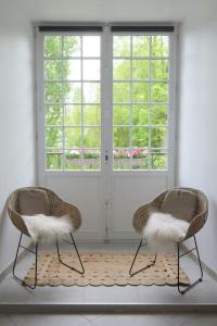 2 chaises assises dans une pièce avec fenêtre dans l'établissement Lavilla dorée, à Moret-sur-Loing