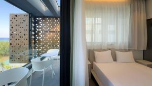 ein Schlafzimmer mit einem Bett und ein Balkon mit einem Tisch in der Unterkunft Sunrise Beachfront Villas - Villa 3 in Paralimni + 56 Fotos