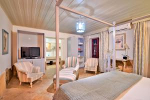 a bedroom with a bed and chairs and a television at Casa de St. Antônio Hotel Boutique in Parnaíba