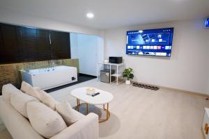 a living room with a white couch and a tv at The Space Hotel Lampang in Lampang