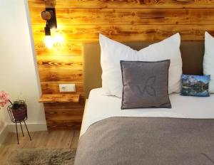 un letto con cuscini bianchi e una parete in legno di Villa Bischofsberg - Lärchen-Wellness Apartment a Windischgarsten