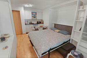 ein kleines Schlafzimmer mit einem Bett und einer Küche in der Unterkunft Studio chaleureux avec vue sur les montagnes in Leukerbad