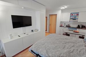 una camera bianca con letto e TV a schermo piatto di Studio chaleureux avec vue sur les montagnes a Leukerbad