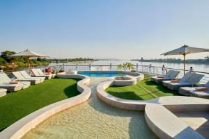 a swimming pool with lounge chairs and a view of the water at Mövenpick Royal Lotus Monday Four Nights Luxor Friday Three nights Aswan in Luxor